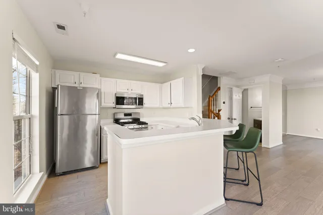 a kitchen with stainless steel appliances a refrigerator a stove a sink dishwasher and a refrigerator with wooden floor