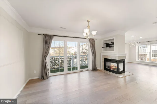 an empty room with fireplace wooden floor and windows