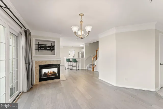 a view of an empty room with wooden floor fireplace and a window