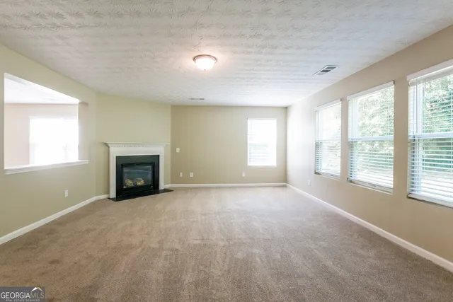 a view of an empty room with a window and fireplace