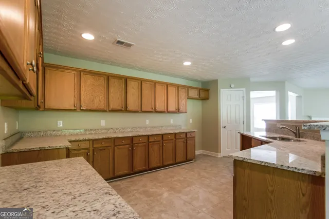 a large kitchen with stainless steel appliances granite countertop a sink and cabinets