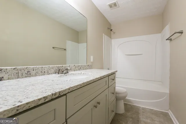 a bathroom with a granite countertop sink a toilet and bathtub