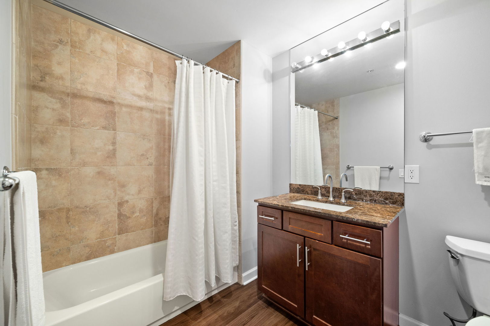 100 East 14th Street, Unit 2809 Chicago, IL 60605 - Photo 19 of 24 a bathroom with a granite countertop sink a mirror a bathtub and shower