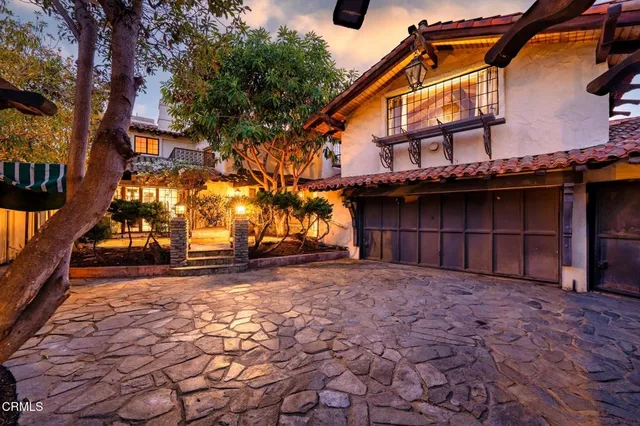 a view of a house with a large tree and wooden fence