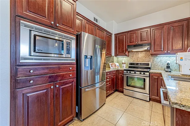 a kitchen with granite countertop a refrigerator stove and oven