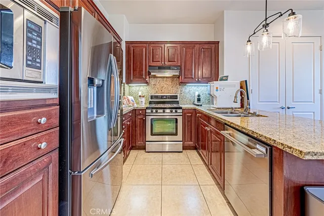 a kitchen with stainless steel appliances granite countertop a refrigerator and a stove top oven