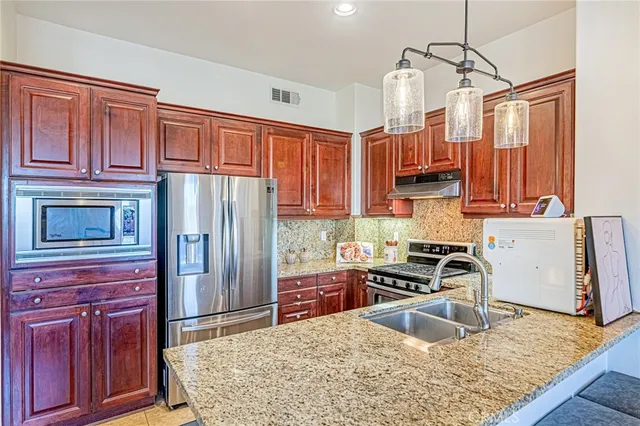 a kitchen with stainless steel appliances granite countertop a refrigerator stove and sink