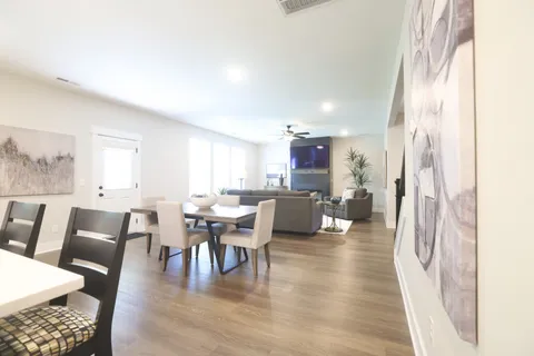 a kitchen with stainless steel appliances a refrigerator a stove a sink and chairs with wooden floor