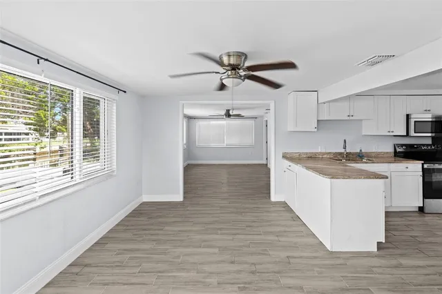 a view of empty room with wooden floor and fan