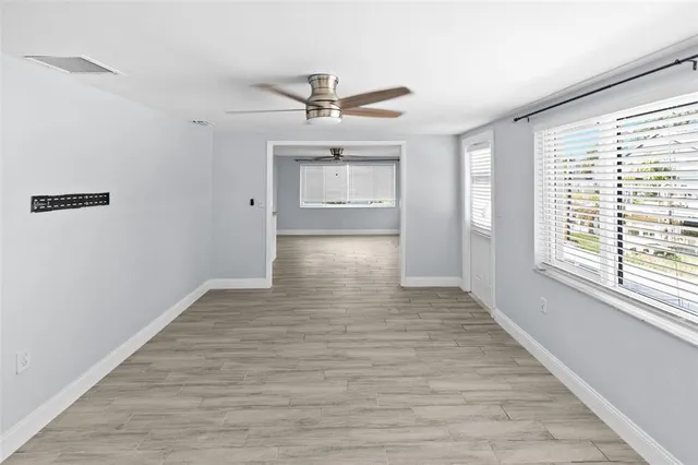 a view of an empty room with a window and wooden floor