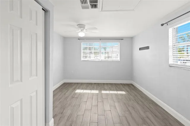 an empty room with wooden floor and windows