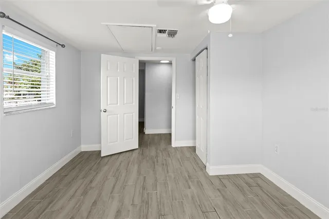 an empty room with wooden floor chandelier fan and windows