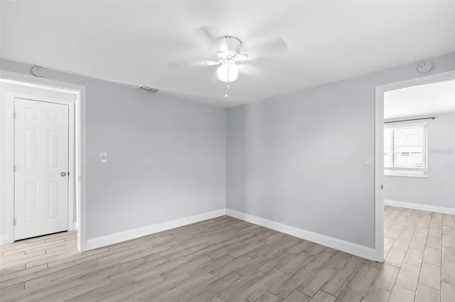 a view of an empty room with a window and wooden floor