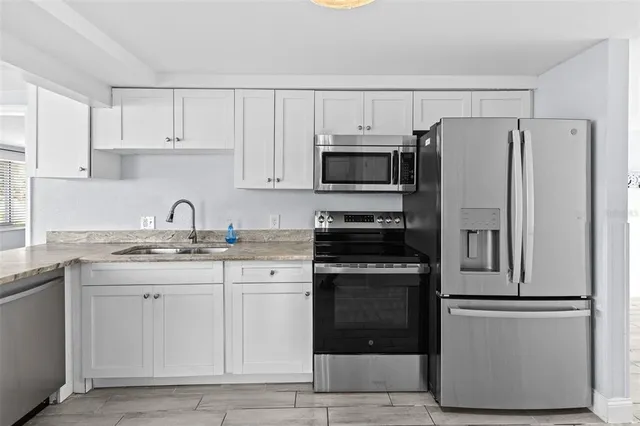 a kitchen with granite countertop a refrigerator stove top oven and sink