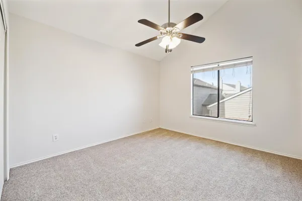 an empty room with a chandelier fan and windows