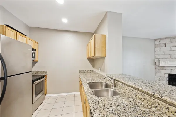 a kitchen with granite countertop a sink a stove and refrigerator