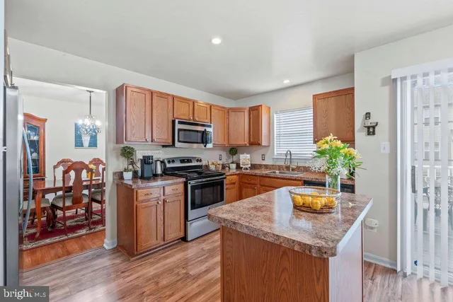 a kitchen with stainless steel appliances granite countertop a refrigerator a stove top oven a sink dishwasher and wooden floor