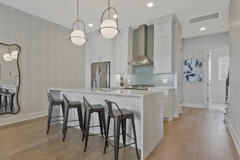 a kitchen with stainless steel appliances granite countertop a table chairs in it and wooden floors