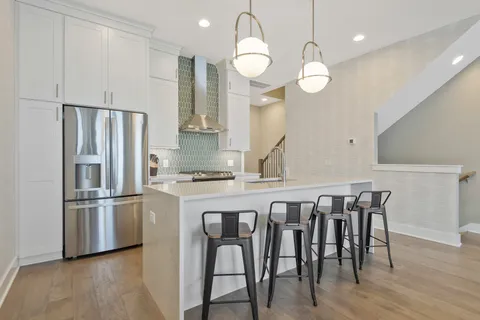 a kitchen with granite countertop a table chairs stainless steel appliances and wooden floor