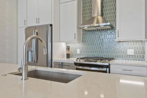a kitchen with a stove a faucet and cabinetry