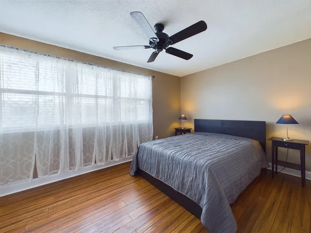 a bedroom with a bed and a large window with wooden floor