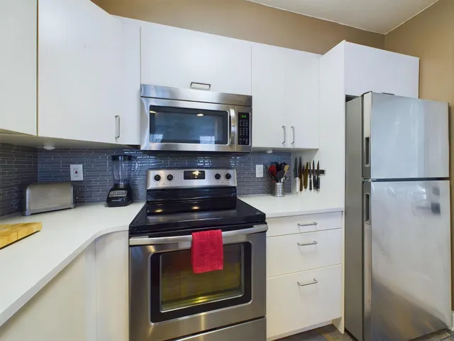 a kitchen with cabinets stainless steel appliances and a counter space