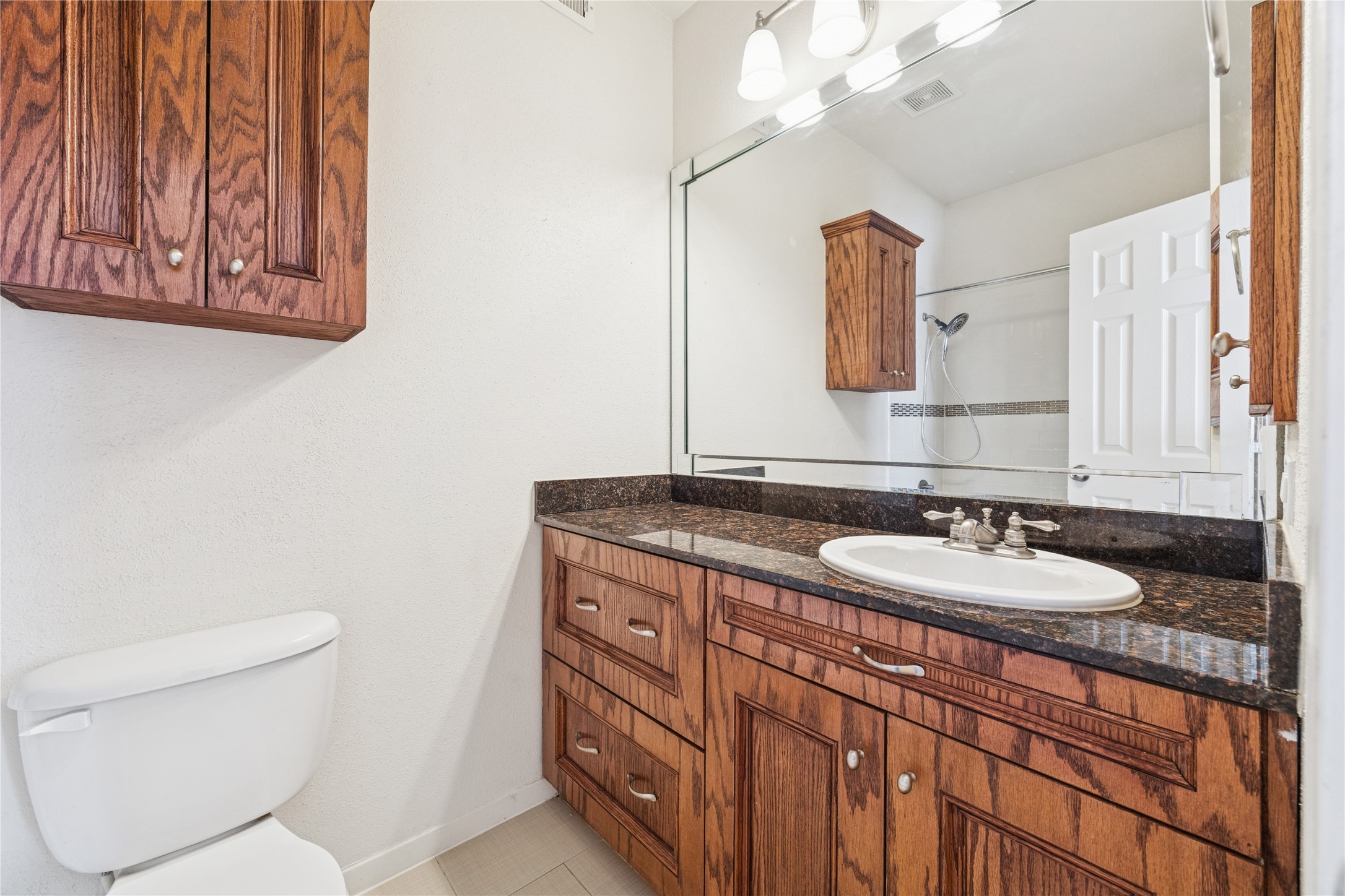 4041 Law Street, Unit 512 Houston, TX 77005 - Photo 10 of 15 a bathroom with a granite countertop sink a mirror and a toilet
