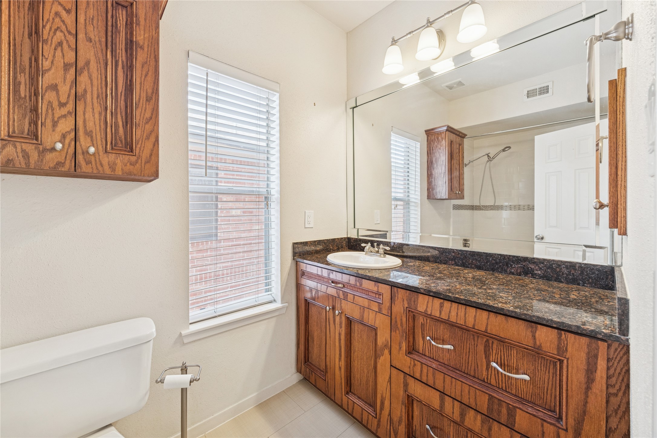4041 Law Street, Unit 512 Houston, TX 77005 - Photo 12 of 15 a bathroom with a granite countertop sink a vanity and a mirror