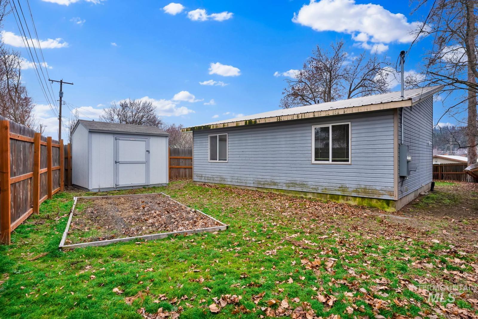4715 West Reeves Street Coeur D'Alene, ID 83814 - Photo 22 of 24 Rear view of property with a fenced backyard, a garden, a shed, and a metal roof