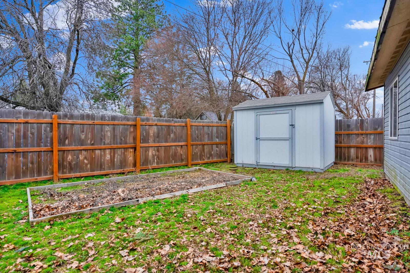 4715 West Reeves Street Coeur D'Alene, ID 83814 - Photo 23 of 24 Fenced backyard with a vegetable garden and a storage shed