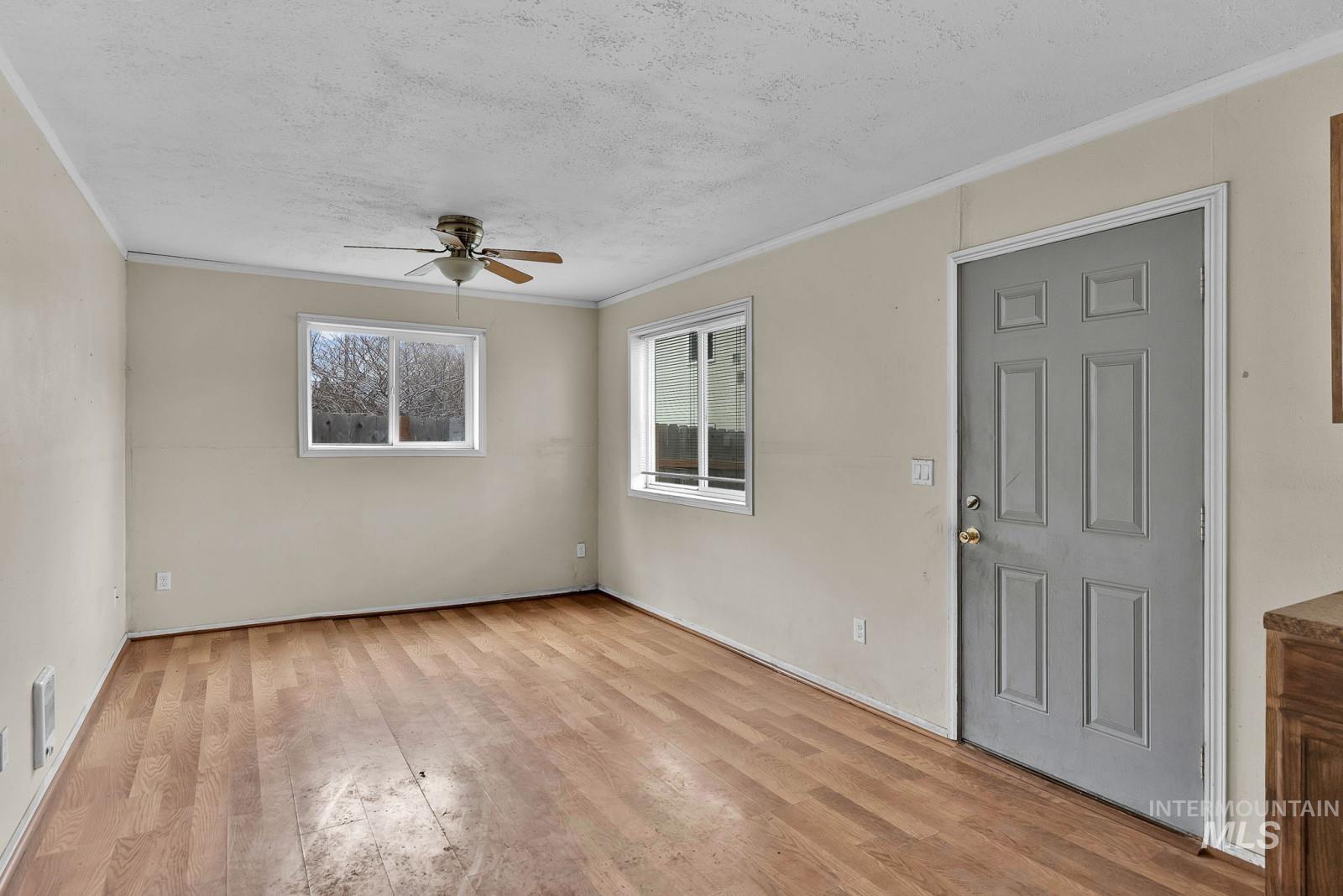 4715 West Reeves Street Coeur D'Alene, ID 83814 - Photo 5 of 24 Unfurnished room featuring light wood-style floors, ornamental molding, ceiling fan, and a textured ceiling