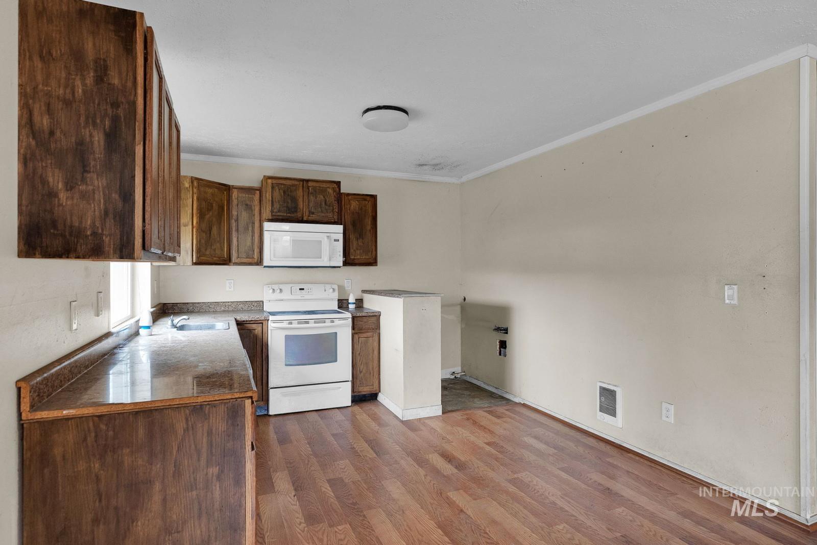 4715 West Reeves Street Coeur D'Alene, ID 83814 - Photo 10 of 24 Kitchen with ornamental molding, white appliances, dark countertops, dark wood finished floors, and dark brown cabinets