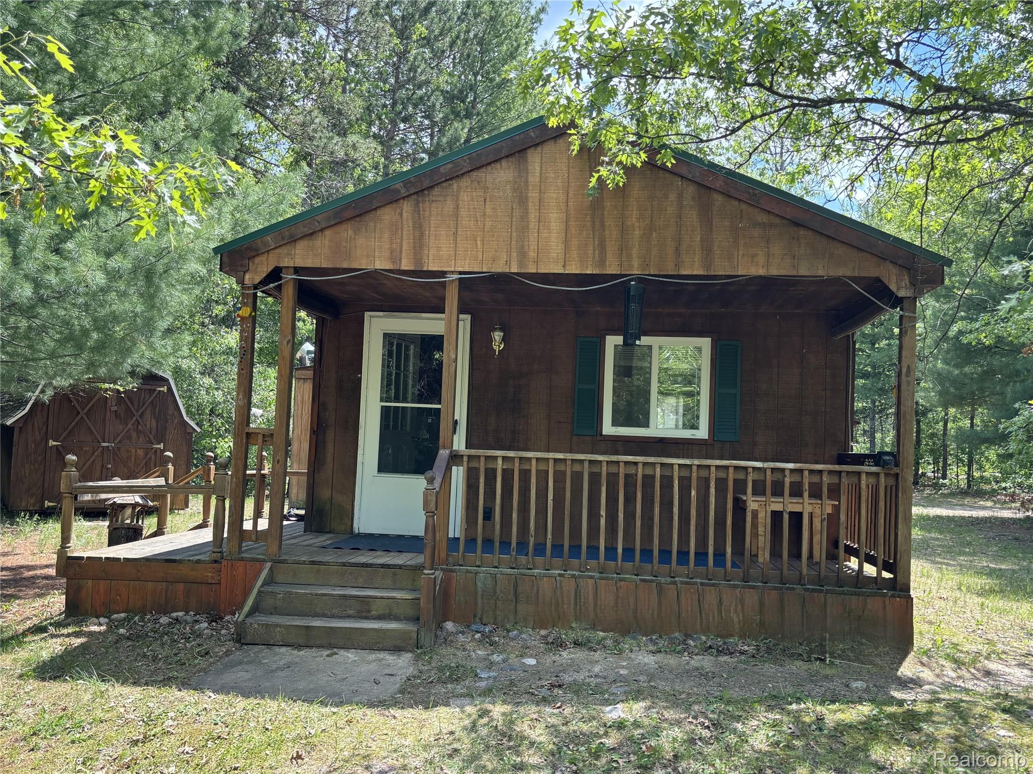 955 Aeronca Road Luzerne, MI 48636 - Photo 2 of 20 Wood-finish exterior featuring a covered front porch with railings and steps