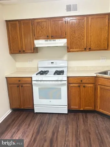 a kitchen with granite countertop wooden cabinets and a stove