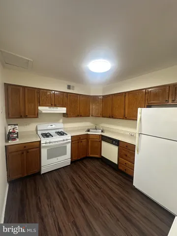 a kitchen with stainless steel appliances granite countertop a stove a sink dishwasher a refrigerator white cabinets and wooden floor