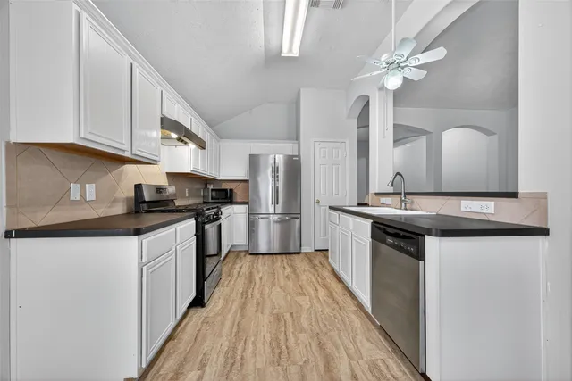 a kitchen with granite countertop white cabinets and white appliances