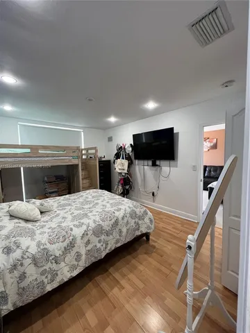 a bedroom with a bed and a flat tv screen on wall