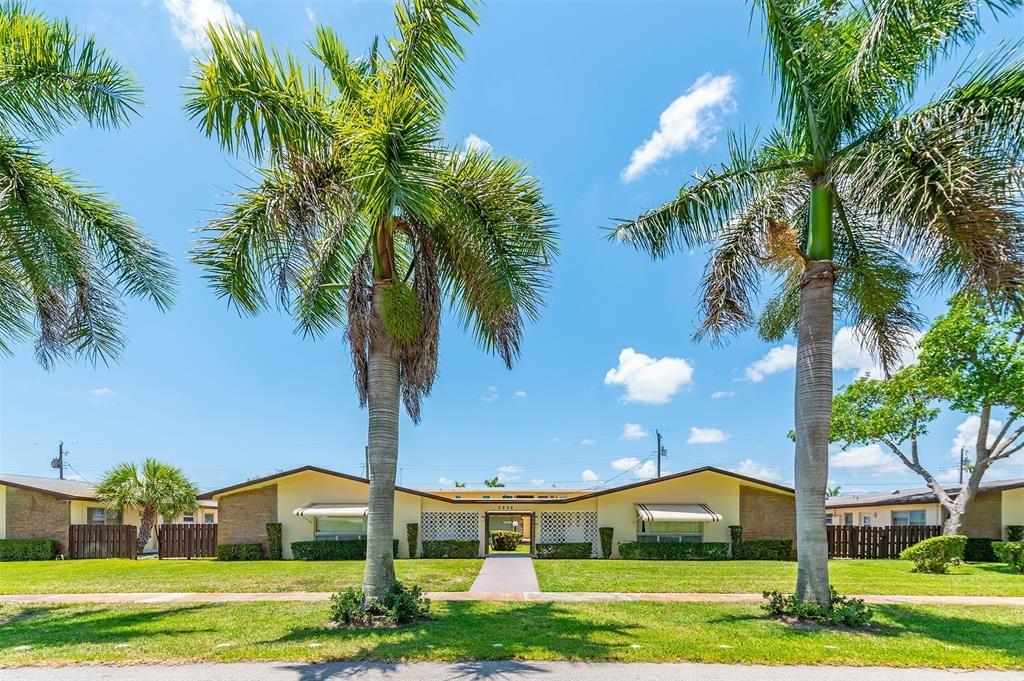 a view of a big house in a big yard with palm trees