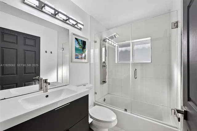 a bathroom with a double vanity sink toilet mirror and shower