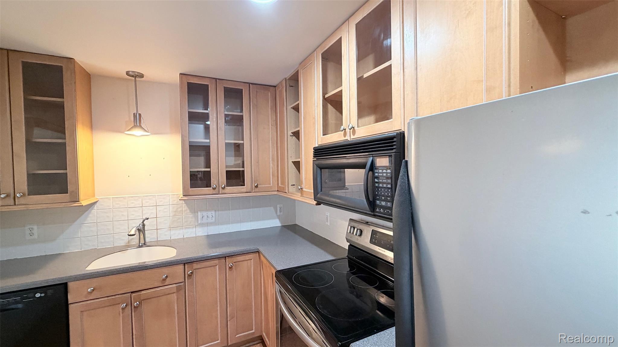 24219 Evergreen Road, Unit 39 Southfield, MI 48075 - Photo 3 of 11 Kitchen with black appliances, glass insert cabinets, tasteful backsplash, and open shelves