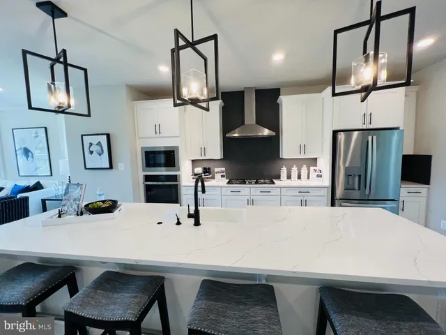 a kitchen with stainless steel appliances a dining table chairs and refrigerator
