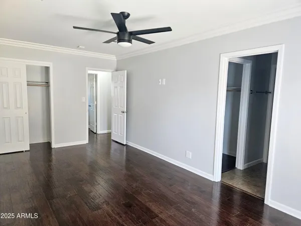 an empty room with wooden floor and a ceiling fan