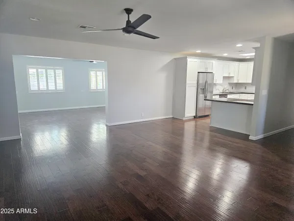 a view of a kitchen and an empty room with wooden floor and a kitchen