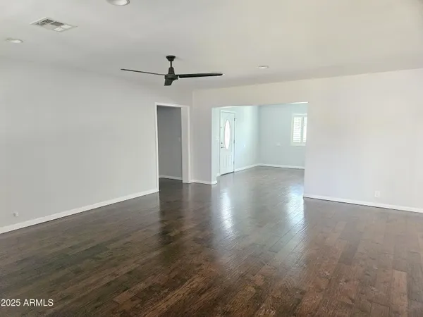 an empty room with wooden floor fan and windows