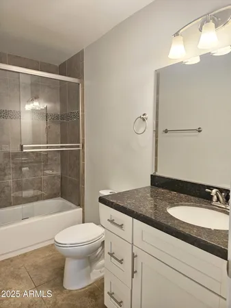 a bathroom with a granite countertop sink a toilet and shower