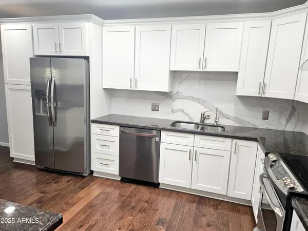 a kitchen with stainless steel appliances granite countertop a refrigerator and white cabinets