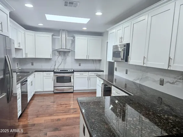 a kitchen with stainless steel appliances granite countertop a sink stove and refrigerator