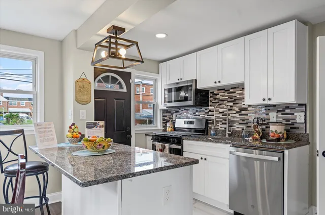 a kitchen with stainless steel appliances granite countertop a stove a sink dishwasher and a microwave with wooden cabinets