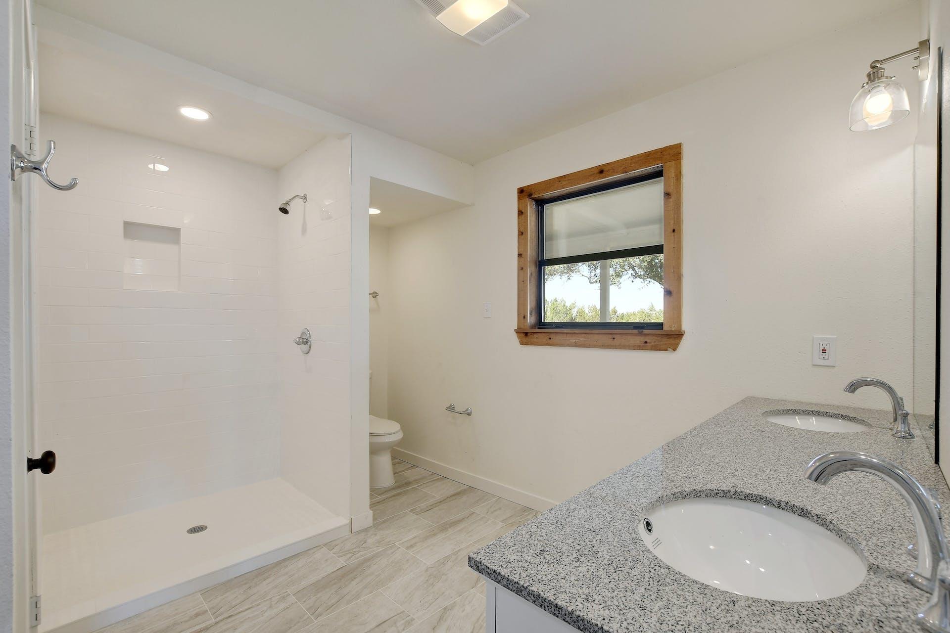 501 Myers Creek Road Dripping Springs, TX 78620 - Photo 15 of 33 Polished stone counters and clean tile flooring define this modern primary bathroom design.