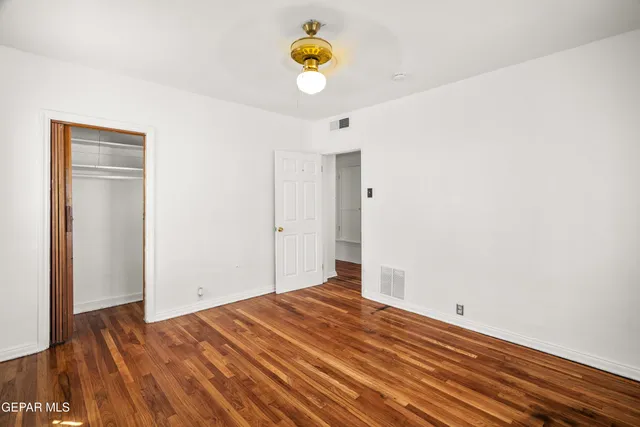 a view of empty room with wooden floor and fan